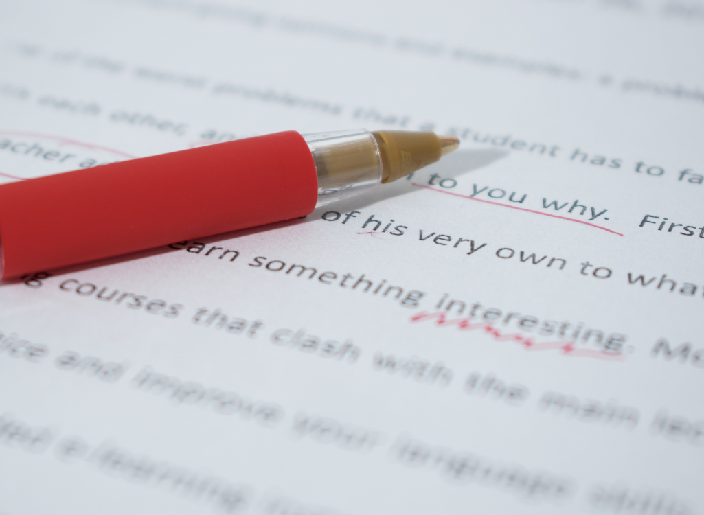 Image of red pen marking a written document to show changes need to be made to the tone of voice